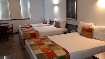 A hotel room with two beds, a desk, and a chair.