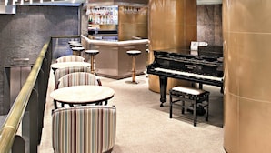 A bar area with a piano, striped chairs, and a bar counter with bottles and glasses. - Hotel Atlantico Star (Rio de Janeiro)