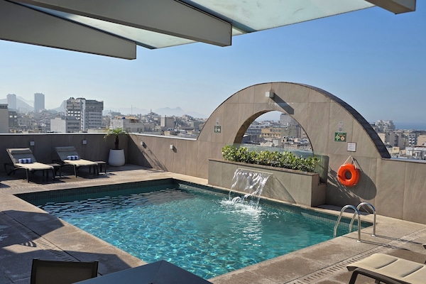 Una piscina al aire libre, sombrillas, sillones reclinables de piscina