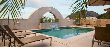 Una piscina al aire libre, sombrillas, tumbonas