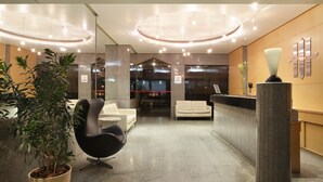 A modern reception area with a reception desk, seating, and a potted plant. - Majestic Rio Palace Hotel (Rio de Janeiro)