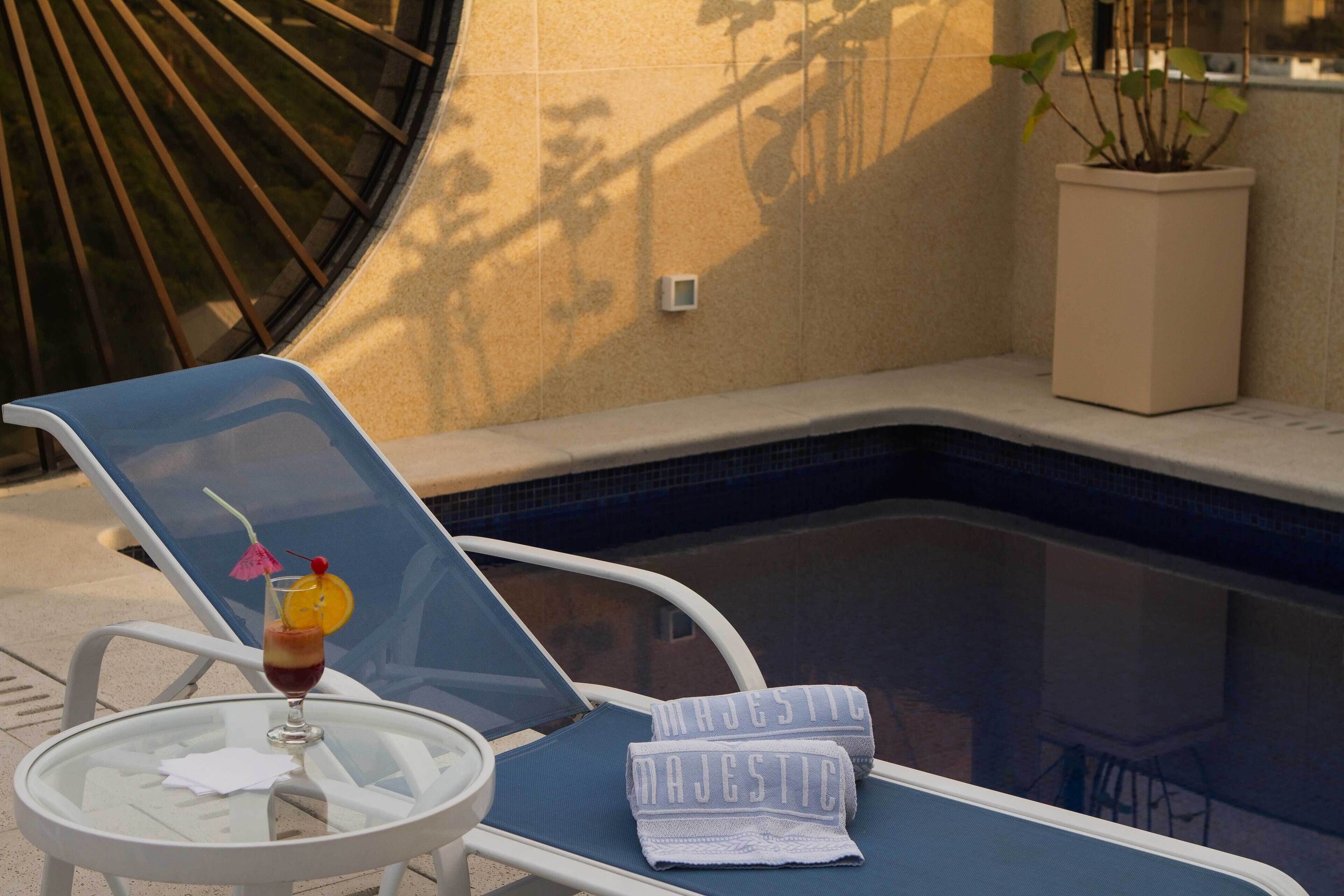 Una piscina al aire libre, sillones reclinables de piscina