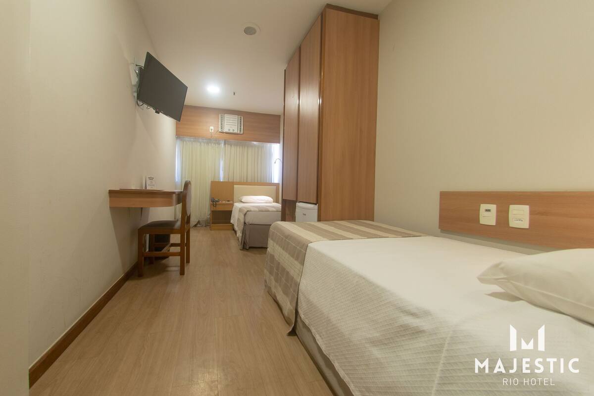 A hotel room with a bed, a desk, a chair, and a wardrobe.