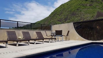 Een buitenzwembad, ligstoelen bij het zwembad