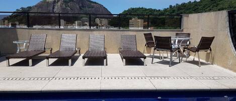 Zona de piscina en la azotea con sillones y vistas a la montaña.