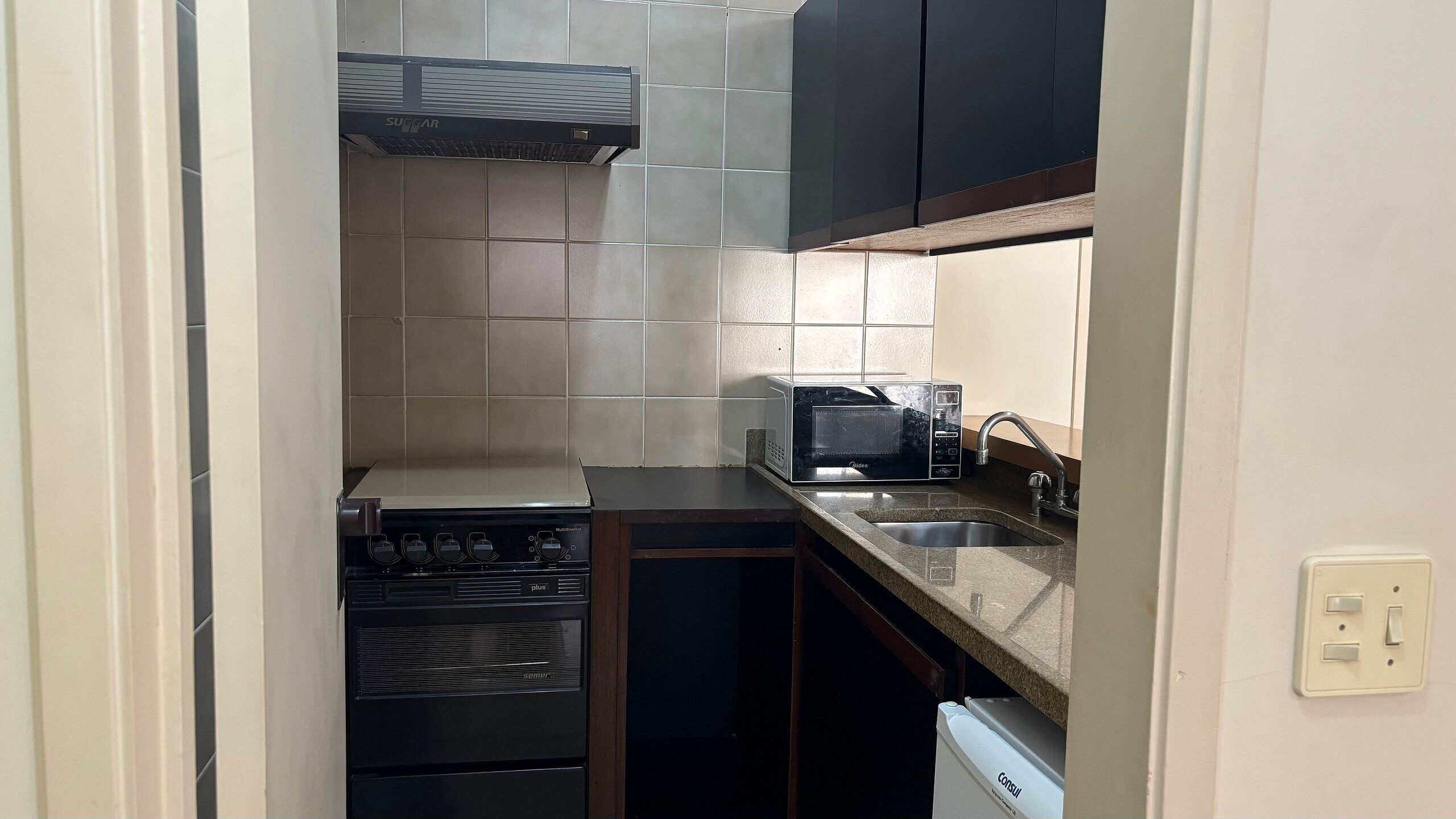 A compact kitchen with a stove, microwave, and sink.