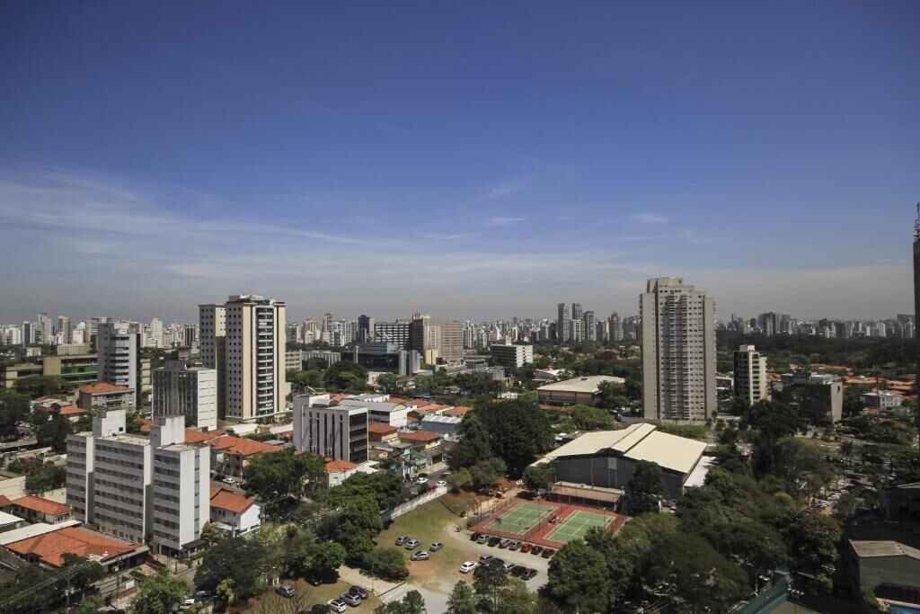 A high-rise building with multiple floors, surrounded by other buildings and greenery.