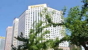 A multi-story hotel with a prominent 'Shangri-La' sign, surrounded by other buildings and trees. - Shangri-La Changchun (Changchun)