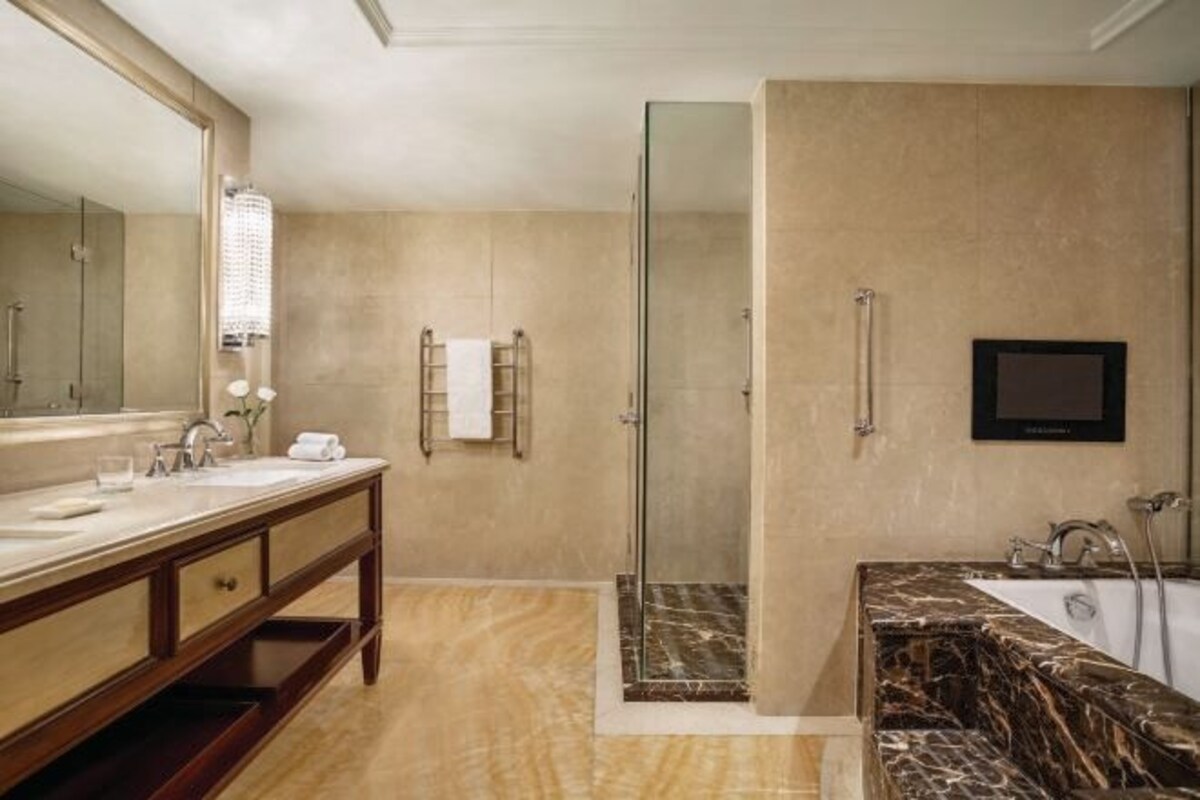 A bathroom with a marble vanity, a glass-enclosed shower, and a large mirror.