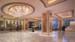 A spacious lobby with a grand chandelier, marble columns, and a reception desk. - Shangri-La Changchun (Changchun)