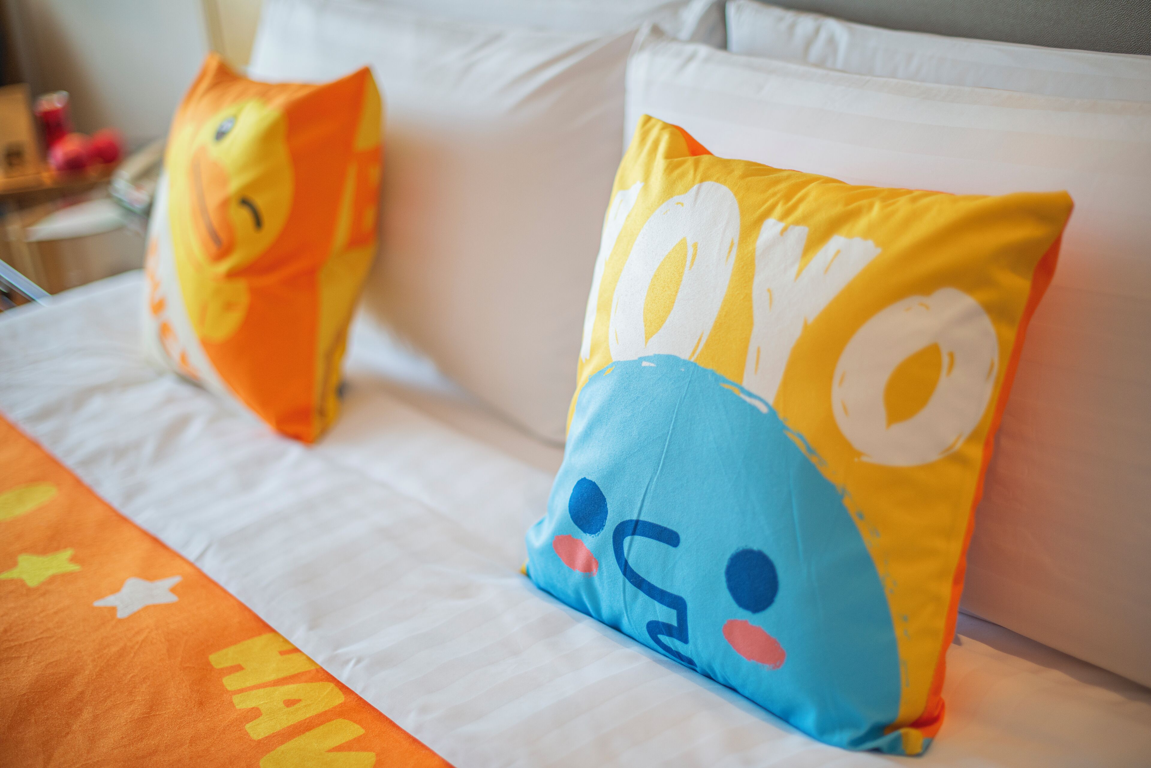 Una cama con dos almohadas, una con un personaje de caricatura y la otra con la palabra "HAYO".