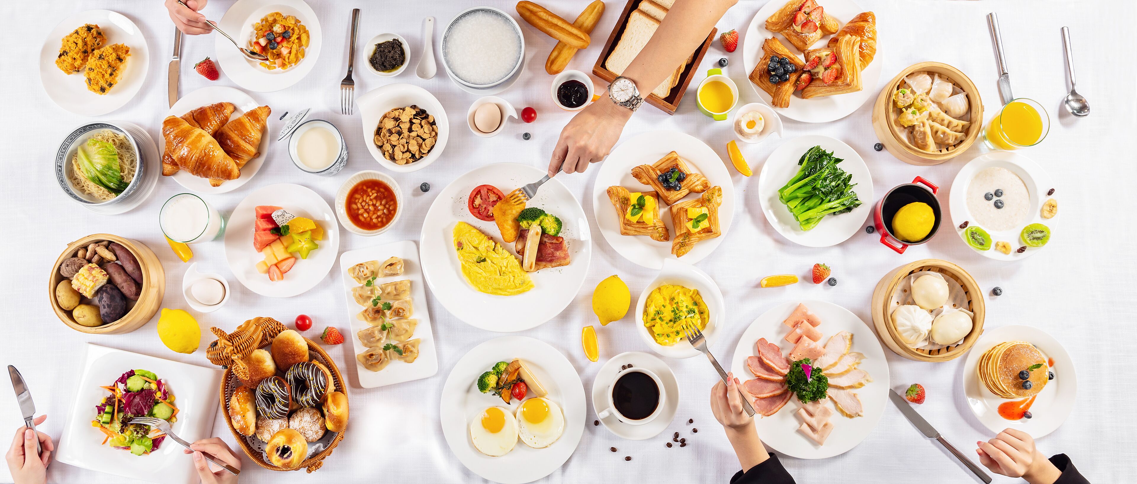 A table with various breakfast dishes, including pastries, fruits, and beverages.