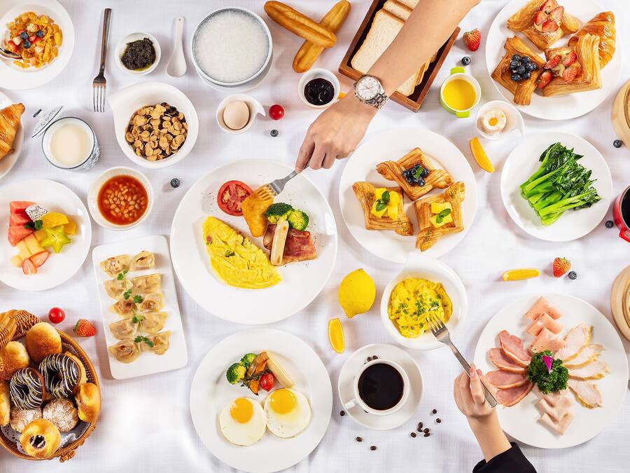 A table with various breakfast dishes, including pastries, fruits, and beverages.