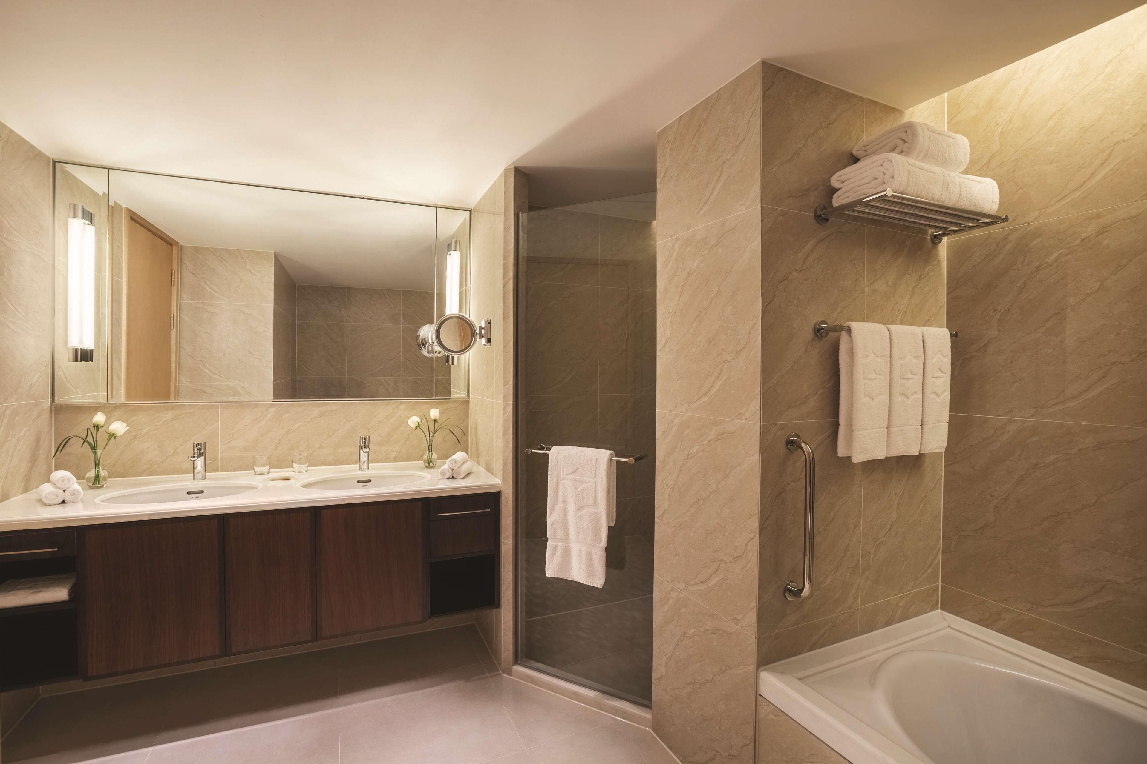 A modern bathroom with a double sink vanity, a glass-enclosed shower, and a bathtub.