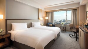 A hotel room with two beds, a desk, a chair, and a view of the city. - Shangri-La Changchun (Changchun)