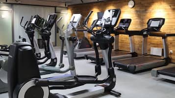 A gym with various cardio machines, including treadmills and ellipticals, arranged in rows.