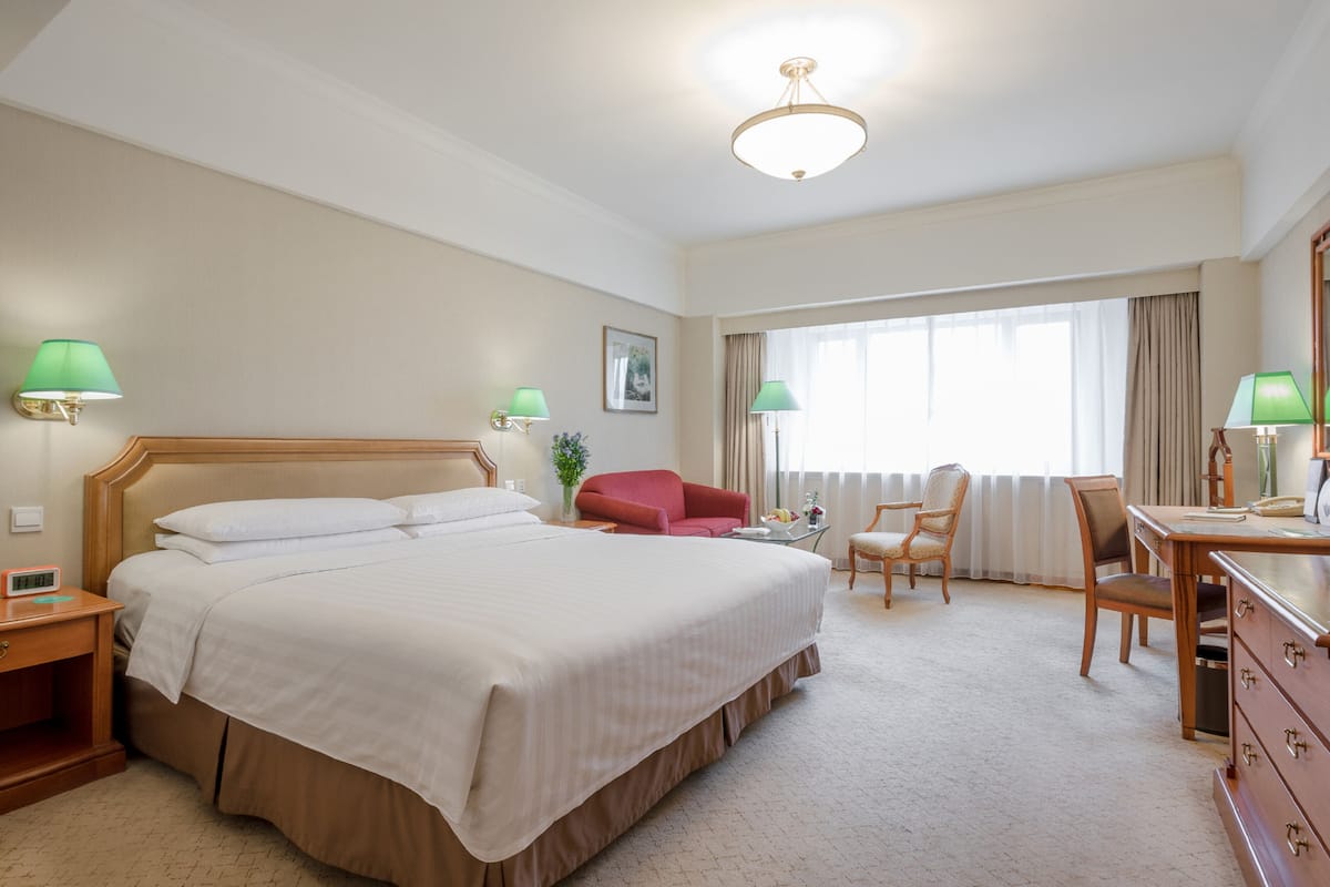 A hotel room with a large bed, a desk, a chair, and a couch.