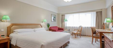 Ein Hotelzimmer mit einem großen Bett, einem Schreibtisch, einem Sessel und einer Couch.