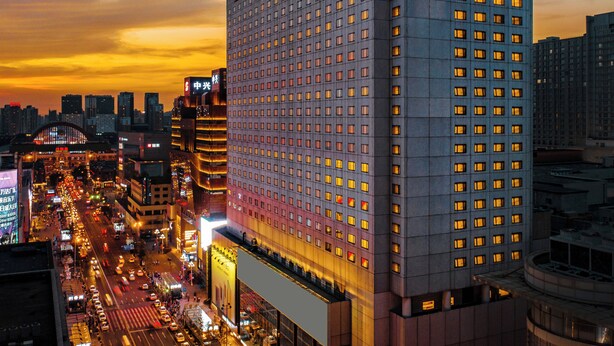 Un hotel moderno de gran altura, con un diseño que destaca por su fachada de ventanas en forma de cuadrícula y una señalización llamativa.