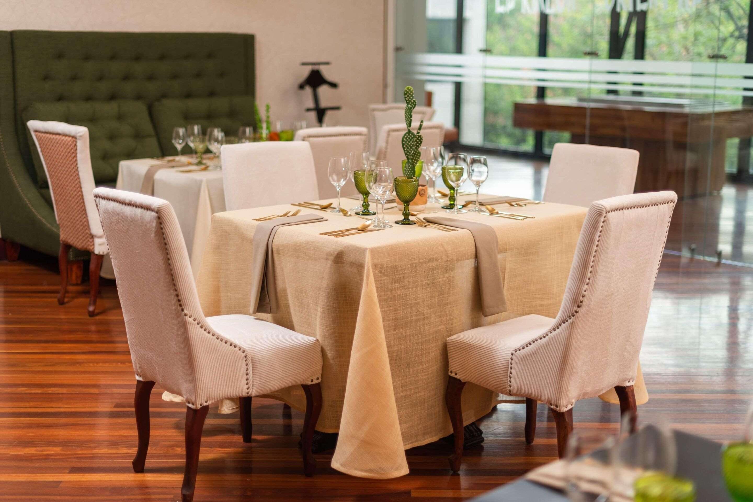 A dining area with a round table set for four, surrounded by upholstered chairs.