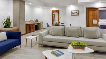 Una sala de estar moderna con un sofá, un diván azul, una mesa de centro y un comedor con mesa de vidrio.