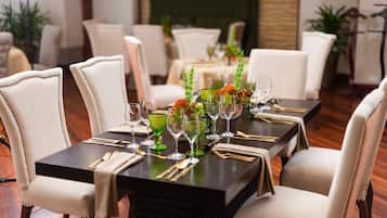 A dining area with a long table set for a meal, surrounded by upholstered chairs.