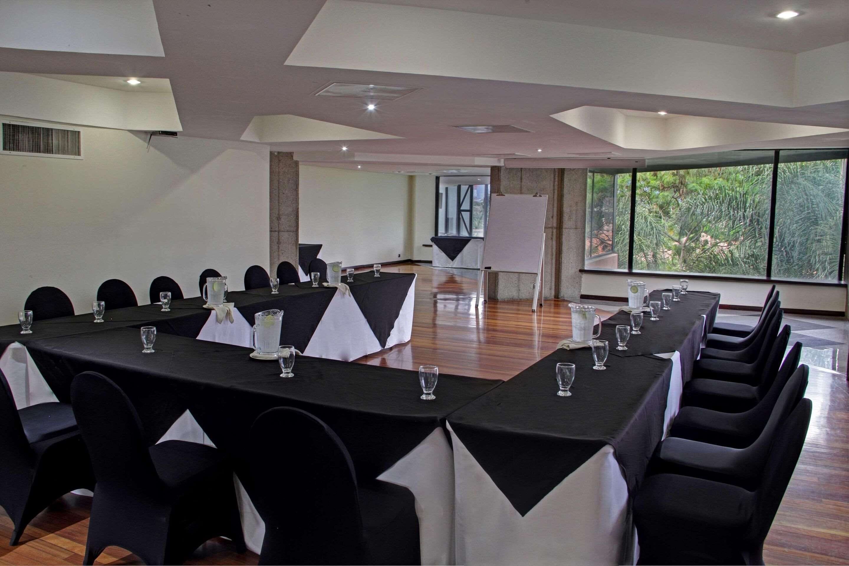 Una sala de conferencias con una larga mesa, manteles blanco y negro y sillas.