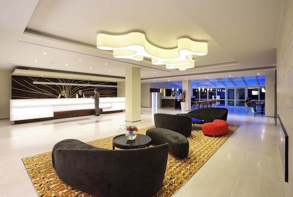 A modern lobby with a reception desk, plush seating, and a patterned rug.
