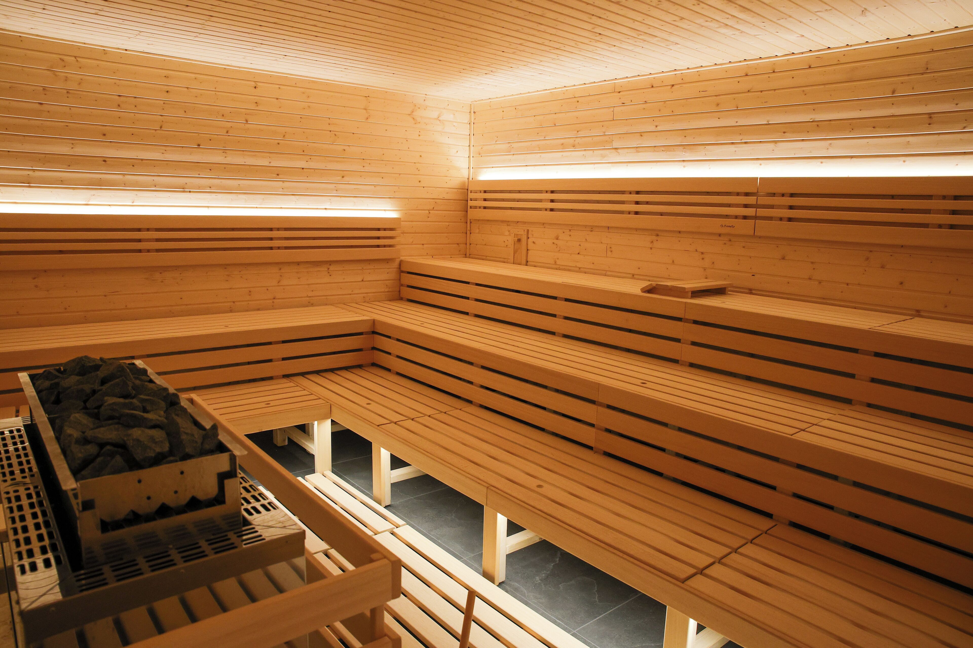 Un sauna avec des bancs en bois et un banc en pierre.