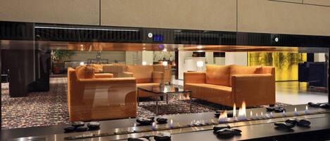 A modern lobby with a seating area, a reception desk, and a decorative water feature with stones and candles.