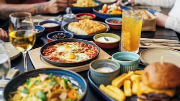 Et spisebord med forskellige retter, herunder pasta, en burger og et glas iste.