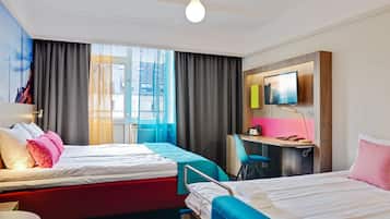 Ein Hotelzimmer mit zwei Betten, einem Schreibtisch, einem Fernseher und einem Fenster mit Vorhängen.