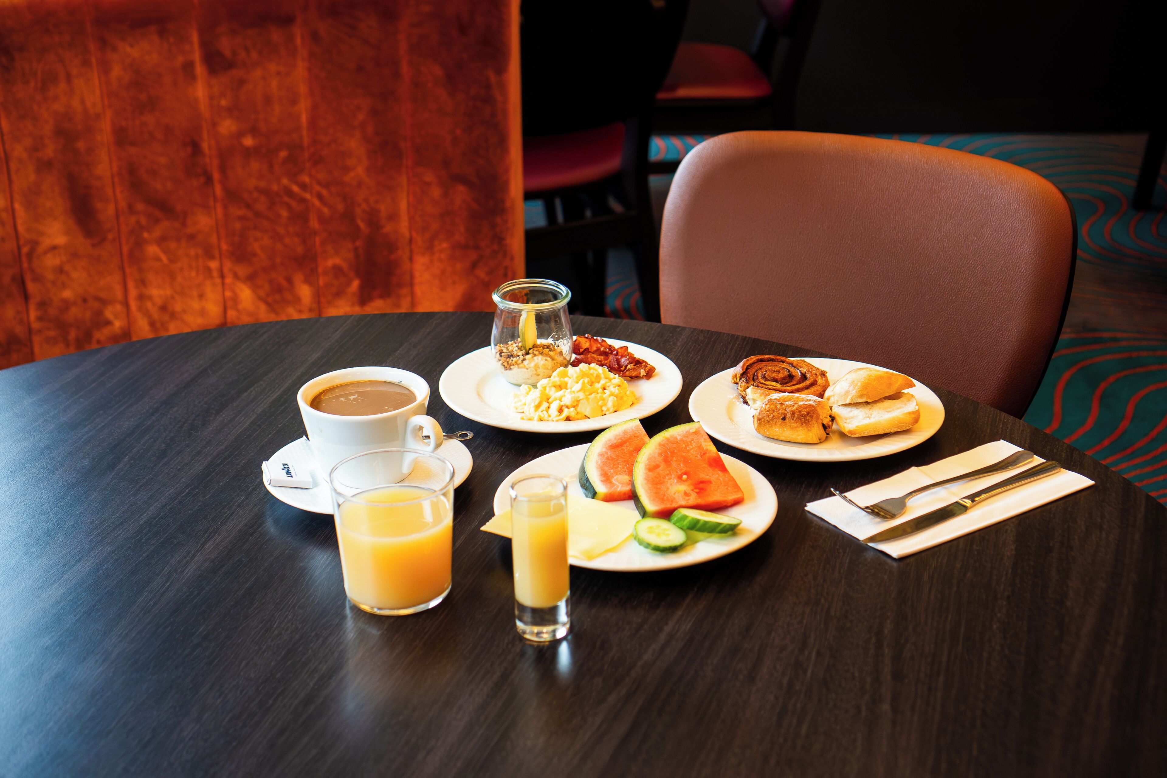 A breakfast table with coffee, juice, eggs, toast, and watermelon.