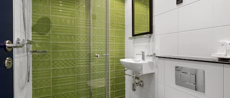 Un baño moderno con ducha de vidrio, lavamanos blanco y un espejo grande.