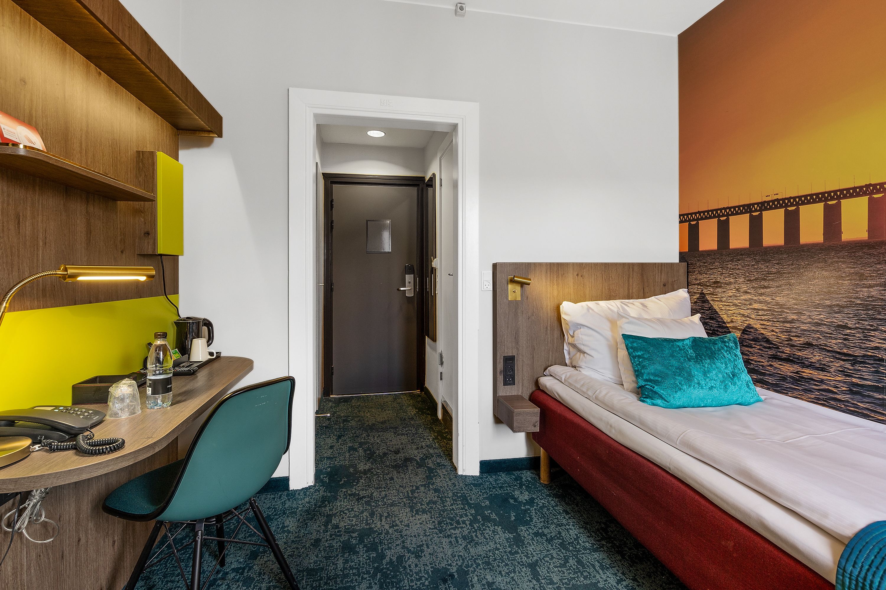 Une chambre d’hôtel équipée d’un bureau, d’une chaise, d’un lit et offrant une vue sur un pont.