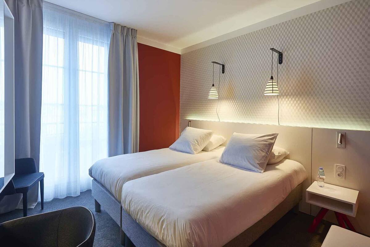 Habitación de hotel con dos camas, un escritorio y una silla.