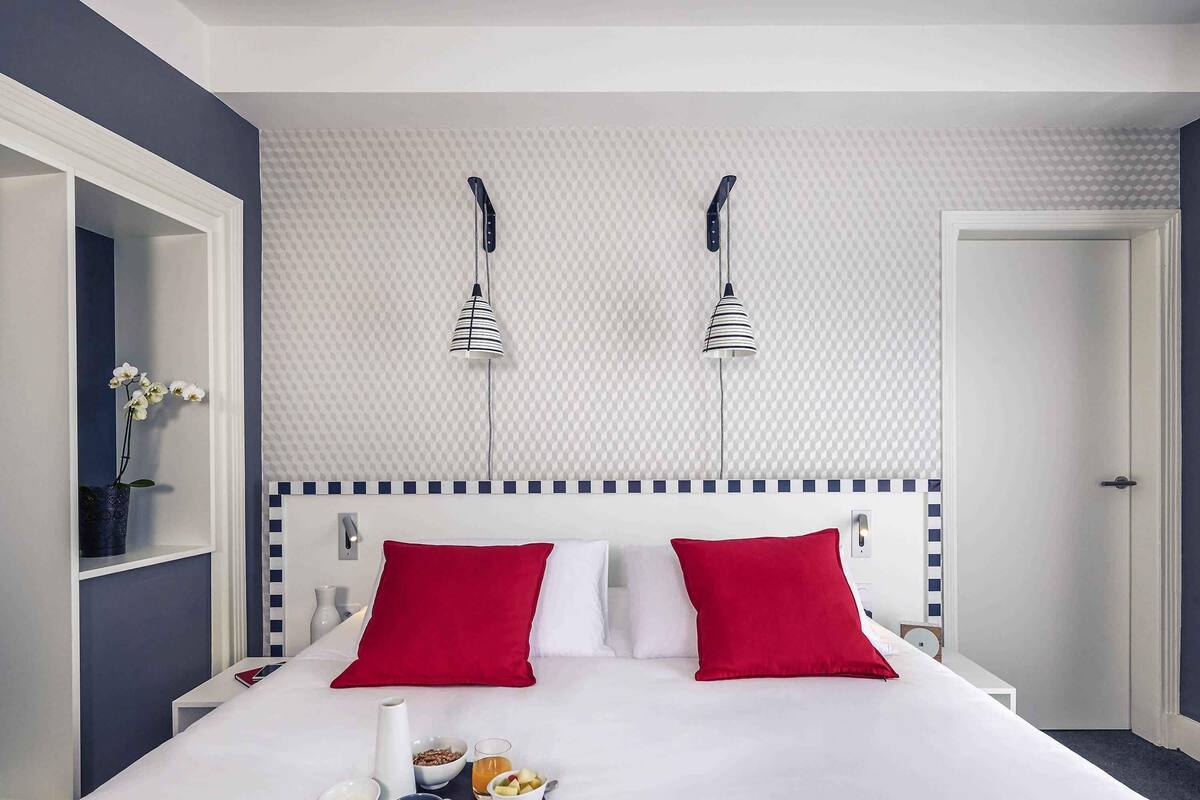 Habitación de hotel con cama, bandeja de desayuno y pared con diseño de cuadros.