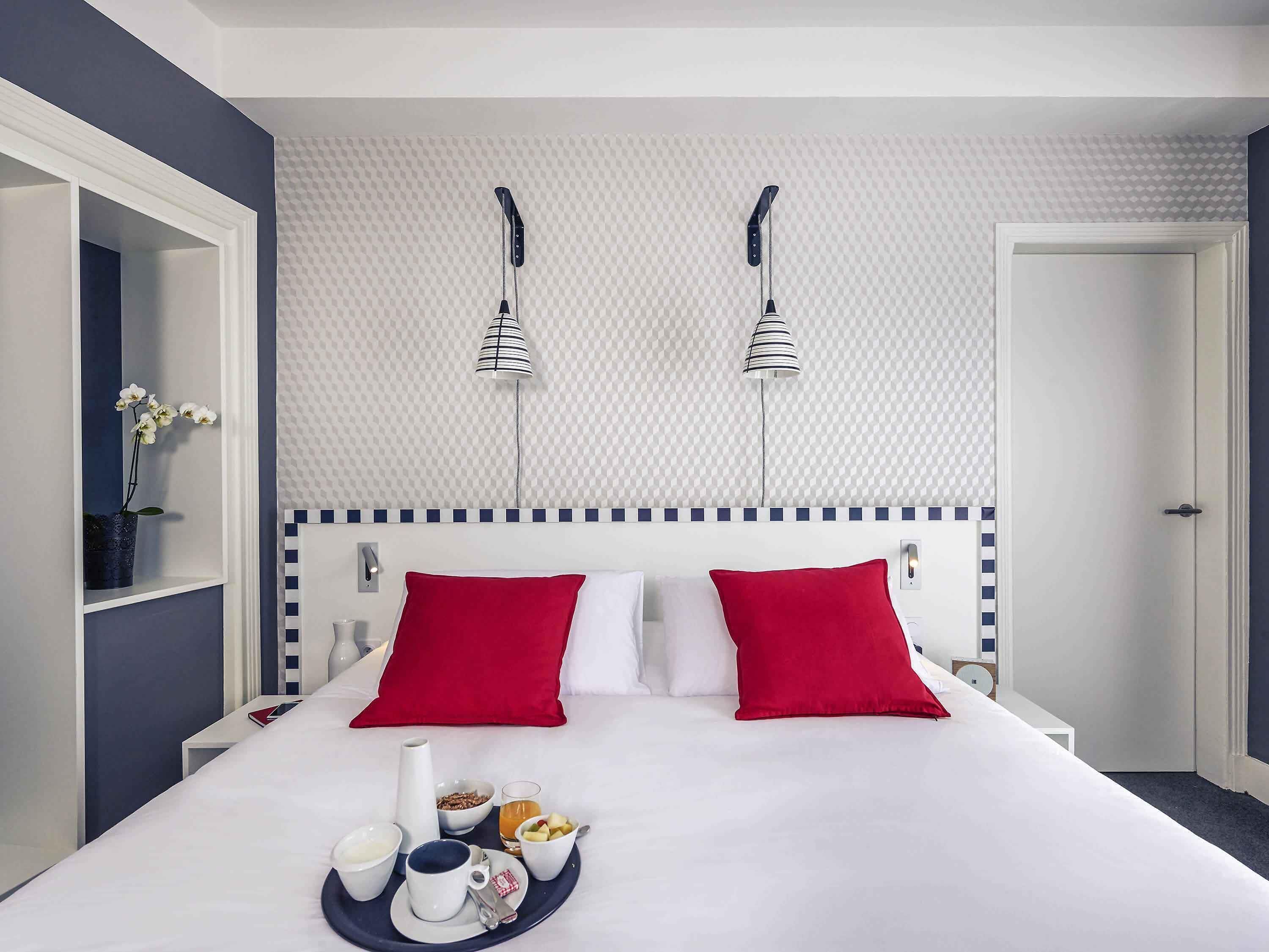 Habitación de hotel con cama, bandeja de desayuno y pared con diseño de cuadros.
