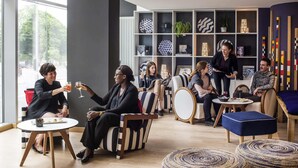 Un espace de détente moderne avec des canapés à rayures, des tables rondes et une bibliothèque agrémentée d’objets décoratifs.
