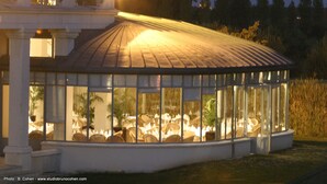 A glass-enclosed structure with tables and chairs, likely a dining area or lounge, with a white exterior and a metal roof. - Mercure Chantilly Resort & Conventions (Vineuil-Saint-Firmin)