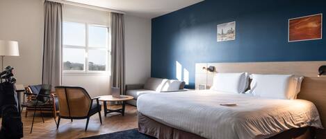 Habitación de hotel con cama, escritorio, silla, ventana y vistas al exterior.