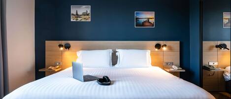 Una habitación de hotel moderna con una cama grande, dos mesitas de noche y dos lámparas de pared.