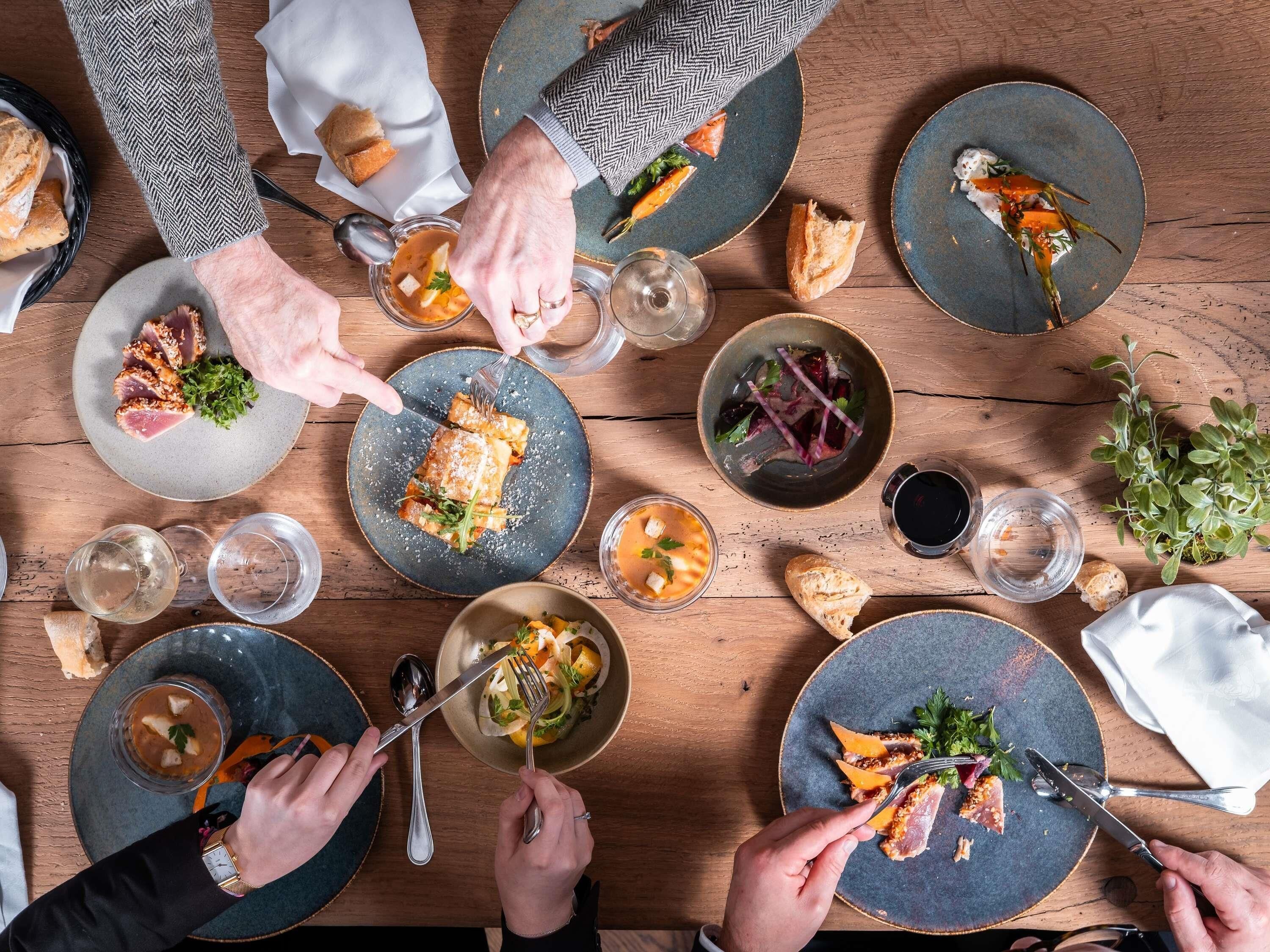 Une table à manger avec de nombreuses assiettes remplies de nourriture, des couverts et des verres.