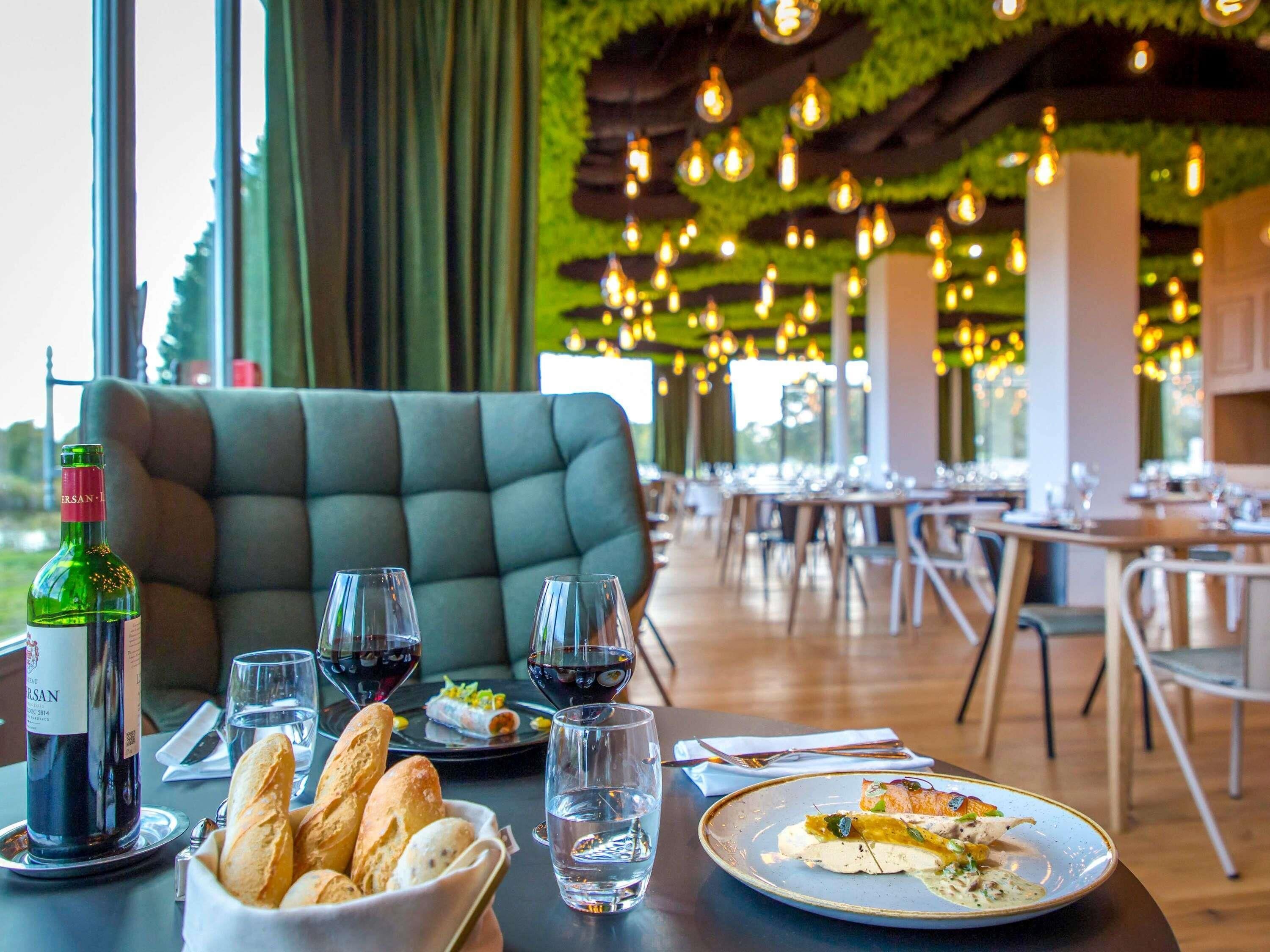 A dining area with tables set for meals, a bottle of wine, and bread on the table.