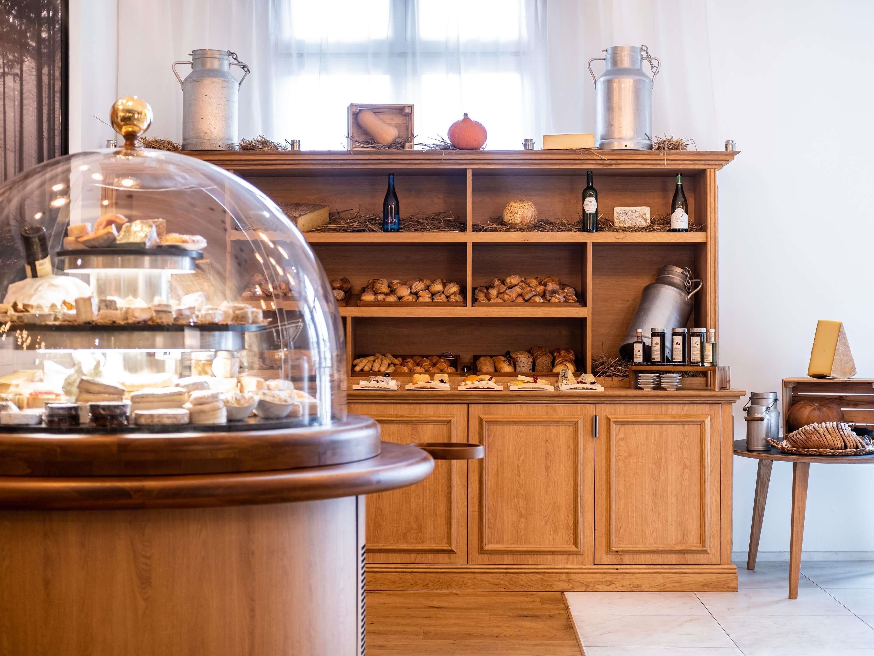 A bakery display with pastries and cheeses, wooden cabinets, and metal containers.