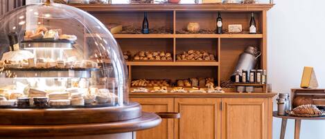 A bakery display with pastries and cheeses, wooden cabinets, and metal containers.