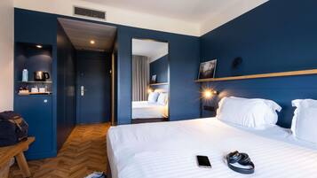 Een hotelkamer met een bed, nachtkastje, spiegel, kledingkast en een zithoek.