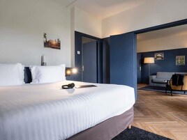 Una habitación de hotel con una cama grande, un escritorio, una silla y un sofá.