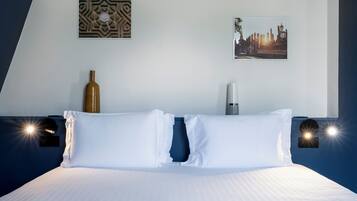 A neatly made bed with white linens, a decorative wall piece, and a framed picture of a cityscape.