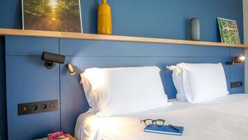 Habitación de hotel con cama, mesitas de noche, una repisa con objetos decorativos y una cámara de seguridad instalada en la pared.